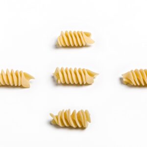 Pasta fusilli oro Verrigni en crudo piezas individuales sobre fondo blanco
