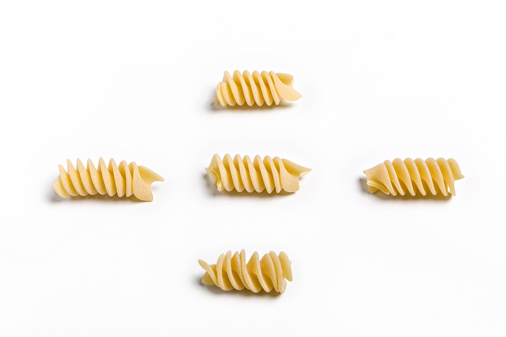 Fusilli Oro Verrigni · detalle del formato | AGÁPICO Pasta fusilli oro Verrigni en crudo piezas individuales sobre fondo blanco