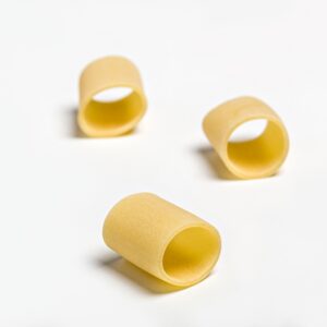 Pasta mezzo pacchero oro Verrigni en crudo piezas individuales sobre fondo blanco