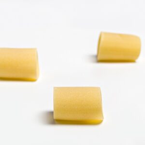 Pasta mezzo pacchero oro Verrigni en crudo vista lateral del formato sobre fondo blanco