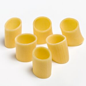 Pasta mezzo pacchero oro Verrigni en crudo vista superior de piezas sobre fondo blanco