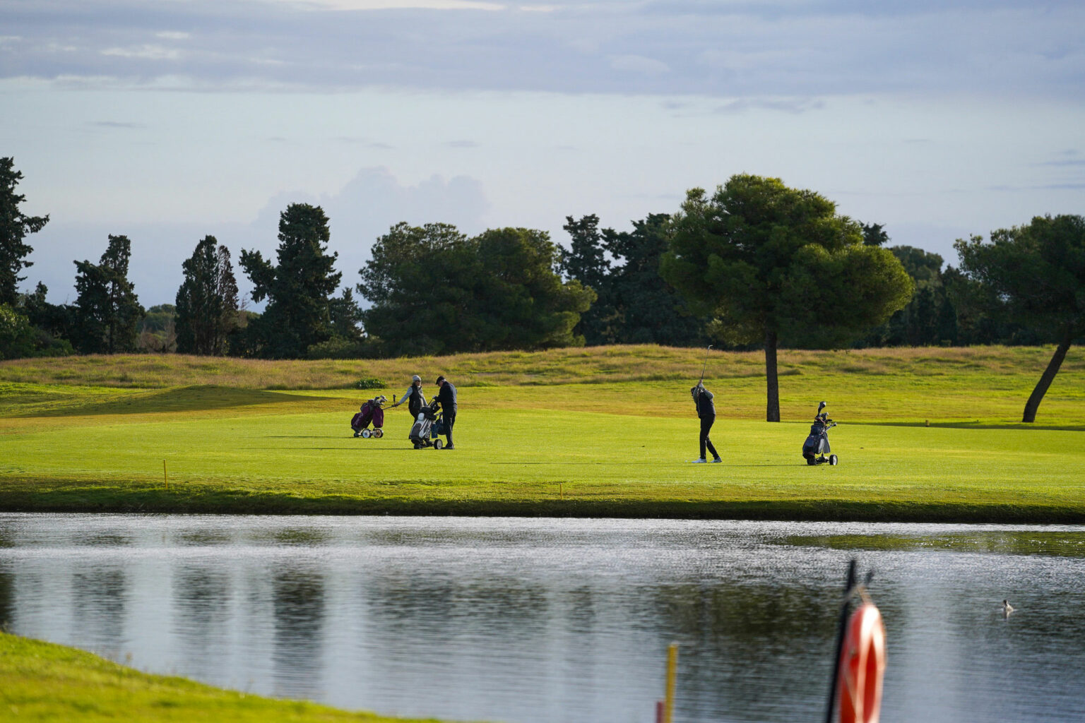 Jugadores durante un torneo de golf celebrado junto al campo y el lago