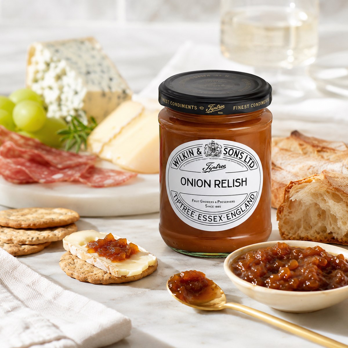 Confitura de Cebolla Tiptree con quesos y crackers Confitura de cebolla Tiptree Wilkin & Sons con quesos, crackers, embutido y vino blanco