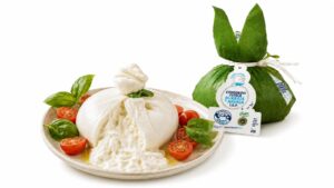 Burrata de Puglia IGP servida con tomate cherry, albahaca y aceite de oliva junto a su envoltorio original
