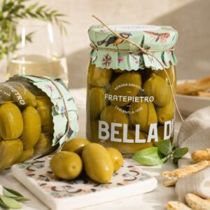 Aceitunas Verdes Bella di Cerignola Fratepietro servidas en tarro de cristal con tapa decorativa y aceitunas en primer plano