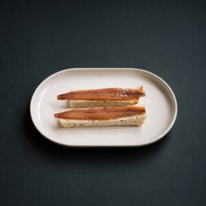 Anchoas del Cantábrico en aceite de oliva Conservas Catalina servidas sobre pan en plato blanco