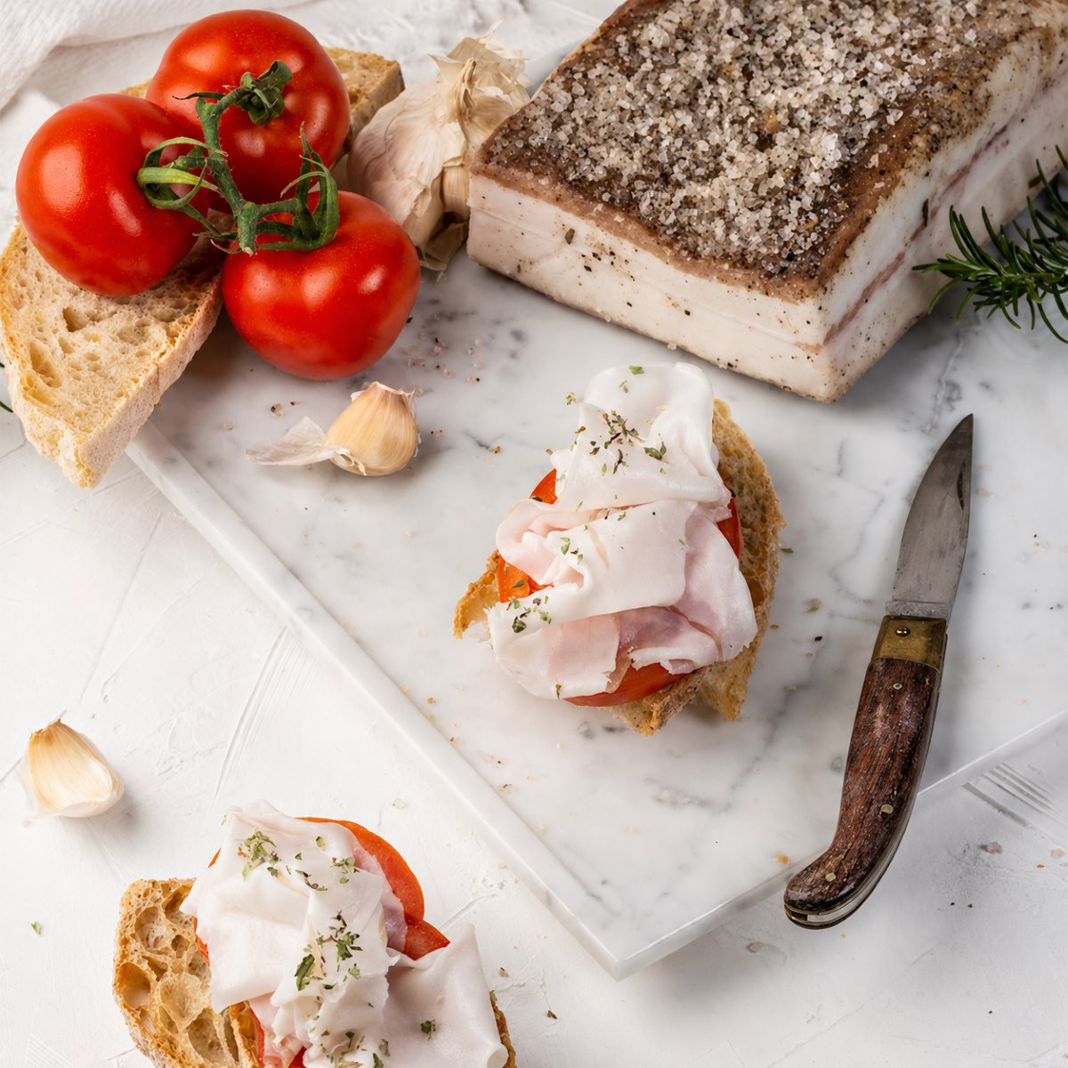 Lardo de Colonnata Antica Larderia Mafalda 350 g Lardo de Colonnata Antica Larderia Mafalda 350 g en lonchas sobre crostini con tomate