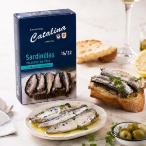 Sardinillas en aceite de oliva Conservas Catalina 16/22 servidas con pan, aceitunas, limón y vino blanco