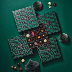 Caja de bombones Neuhaus Special Winter Box abierta con surtido de pralines y decoración navideña.