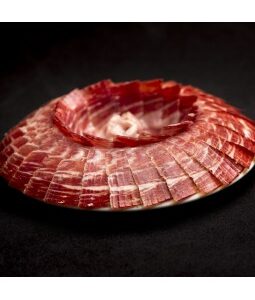 Jamón de bellota 100% ibérico loncheado en presentación circular sobre plato negro