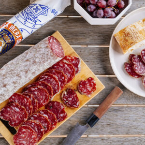 Salchichón de Vic loncheado Casa Riera Ordeix servido en tabla de madera con pan rústico y uvas