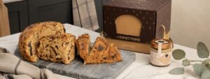 Panettone de chocolate artesanal con estuche y crema gourmet sobre mesa de mármol