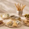 Mesa de entrantes gourmet fríos con conservas, quesos, aceitunas, grissini y vino blanco