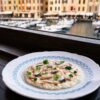 Risotto cremoso con arroz Carnaroli servido frente a un puerto italiano