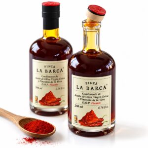 Dos botellas de aceite de oliva con Pimentón de la Vera DOP picante Finca La Barca 200 ml junto a una cuchara de pimentón