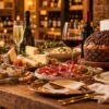 Mesa con vinos blancos, espumosos y tintos, conservas, quesos, embutidos y panettones de chocolate y pistacho.